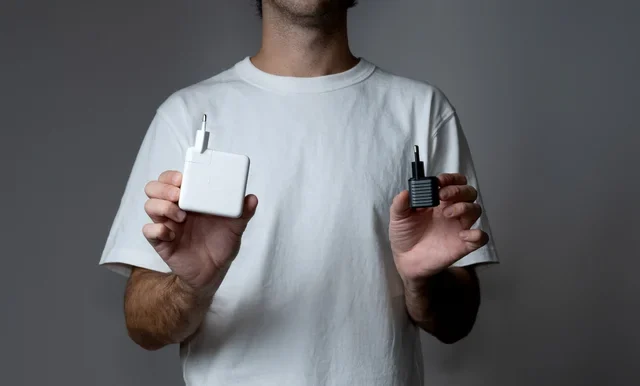 A man holding an Apple charger in one hand and the Supertiny in the other.