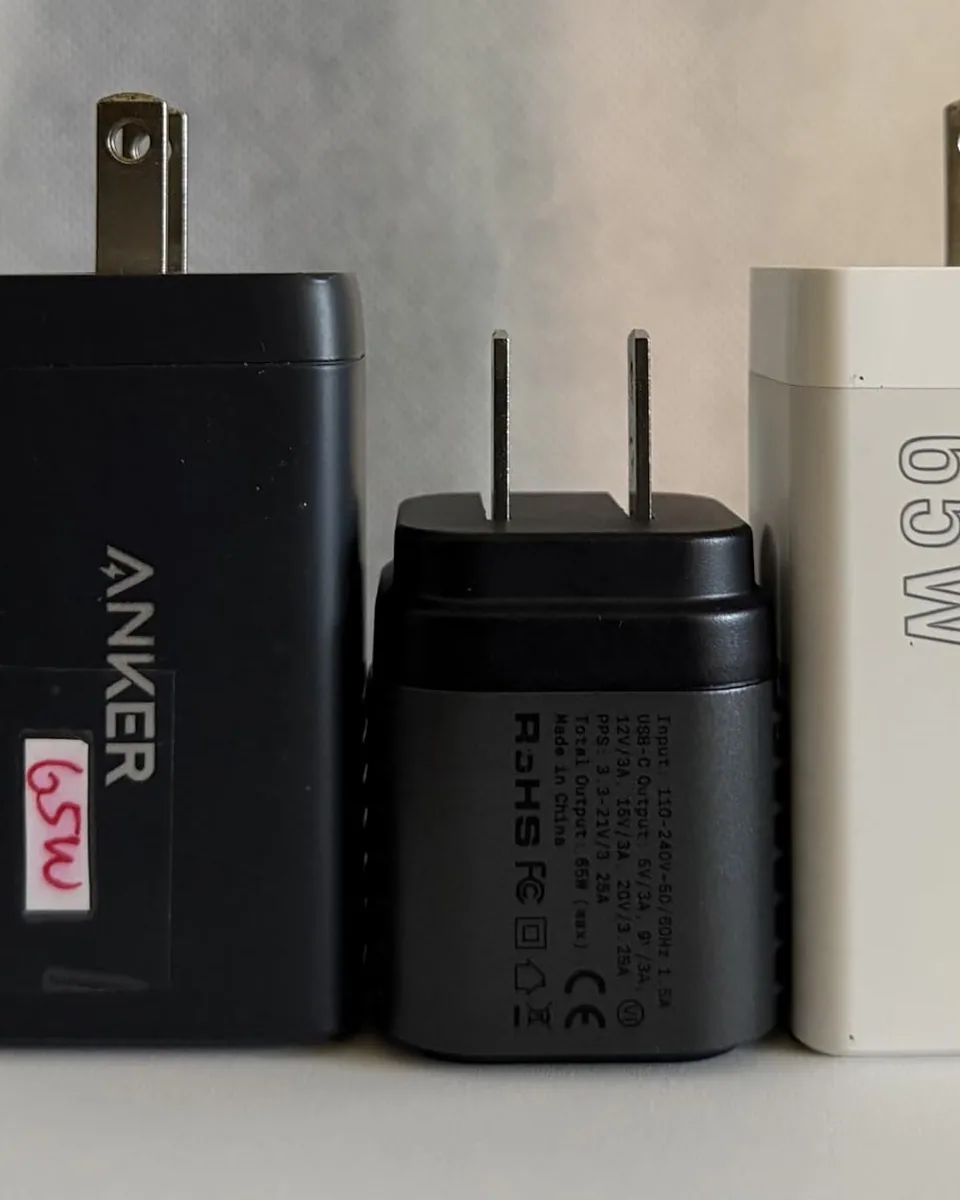A customer photo of the Supertiny between two larger 65W chargers.